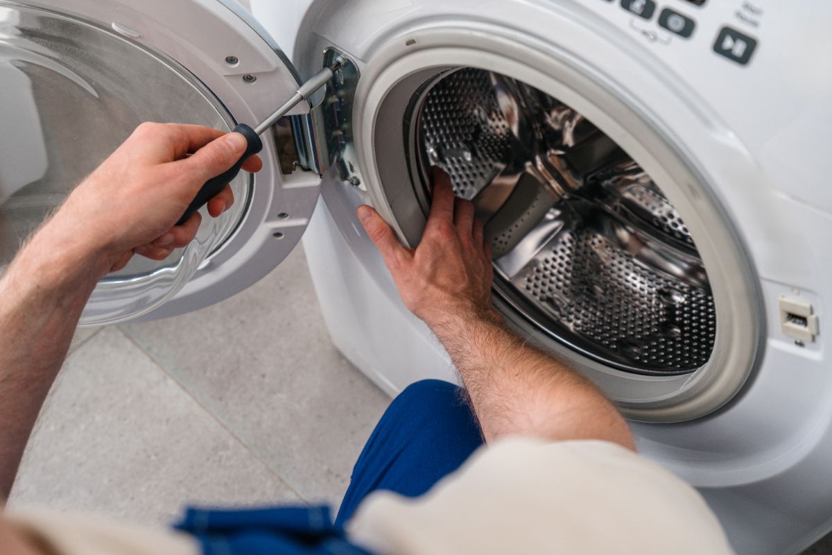 Man opening washing machine door to load laundry